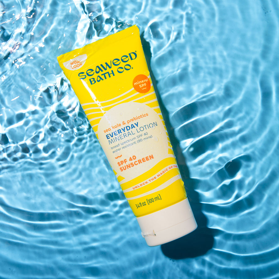 Everyday Mineral Lotion SPF 40 Sunscreen tube laying in rippling water on sky blue background. Seaweed Bath Co.