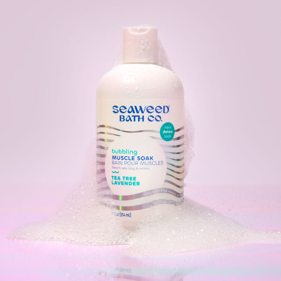 Bubbling Muscle Soak Bottle covered in bubbles on a pink holographic background. Seaweed Bath Co.