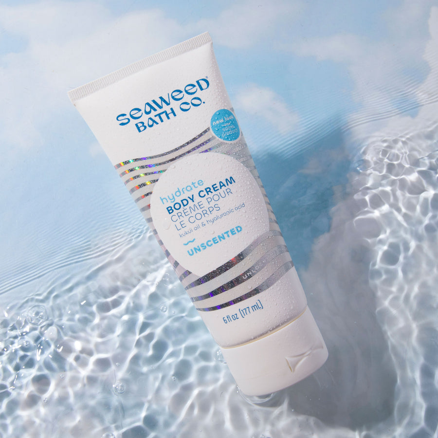 Unscented Hydrate Body Cream tube floating in rippling water on sky blue background. Seaweed Bath Co.
